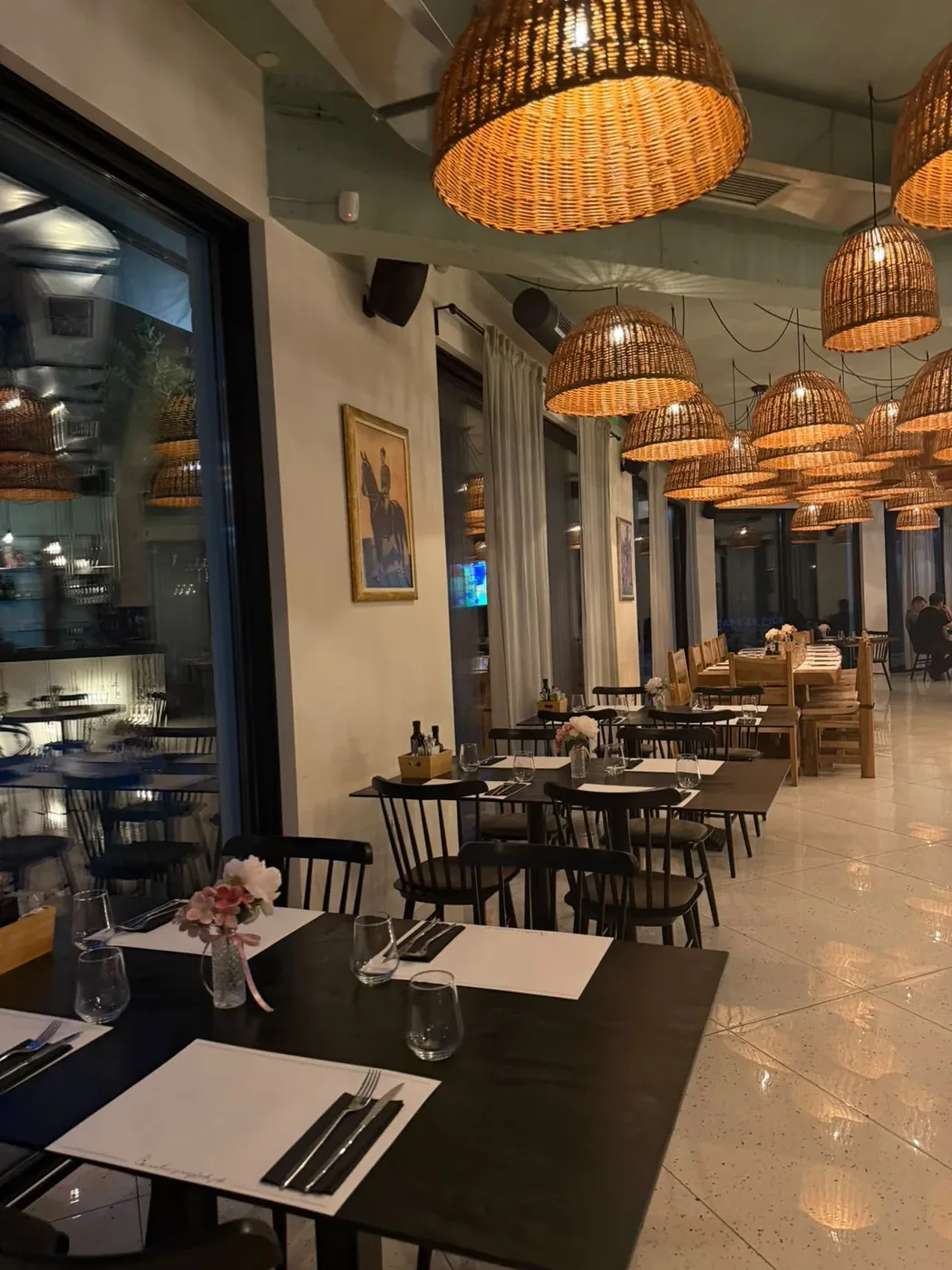 Unutrašnjost restorana U matere s pletenim lusterima i postavljenim stolovima
